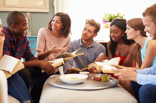 Group of people in discussion around a table, books in hands