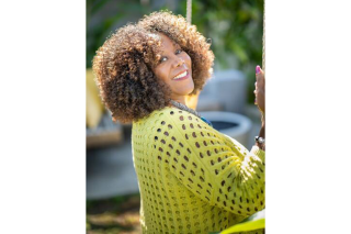 Woman in a posed in a fun over the shoulder, wearing a bright green sweater.