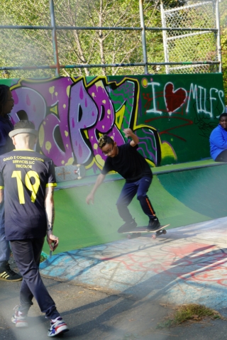 A dad cheers his son on as he demonstrates a skateboarding technique