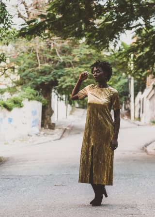 Nathalie Joachim wearing a gold dress and standing outdoors