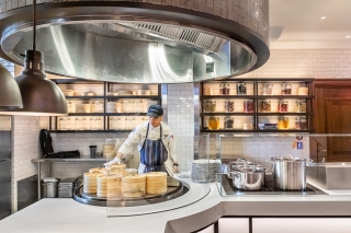 A cook prepares food at Lotus in the Commons Servery