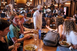 President Salovey dressed in a chef's jacket speaking with a group of students in Commons during lunch