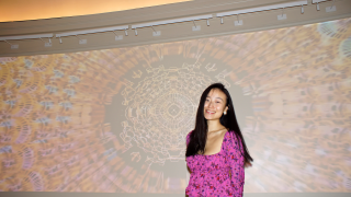 Mary L. Peng '23 MPH standing in front of her projection design exhibit