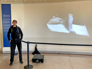 Osvald Landmark '23 MFA standing in front of his projection design exhibit