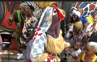 A person in an elaborate costume and mask on a busy street