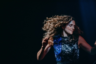 Abigail Washburn on a black background with direct lighting, her hair flying, caught in motion.