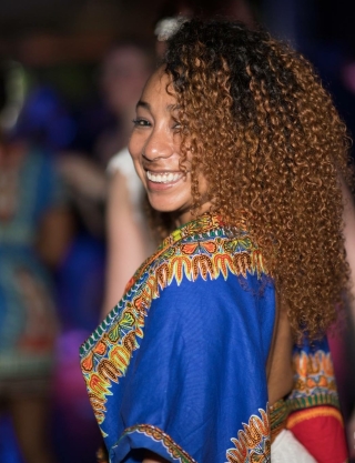 Smiling with full curly hair in blue top.